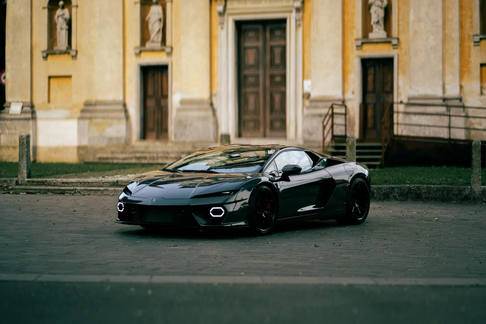 Lamborghini Temerario grigia della flotta GC Auto, vista frontale con fari esagonali a LED accesi in un borgo storico italiano